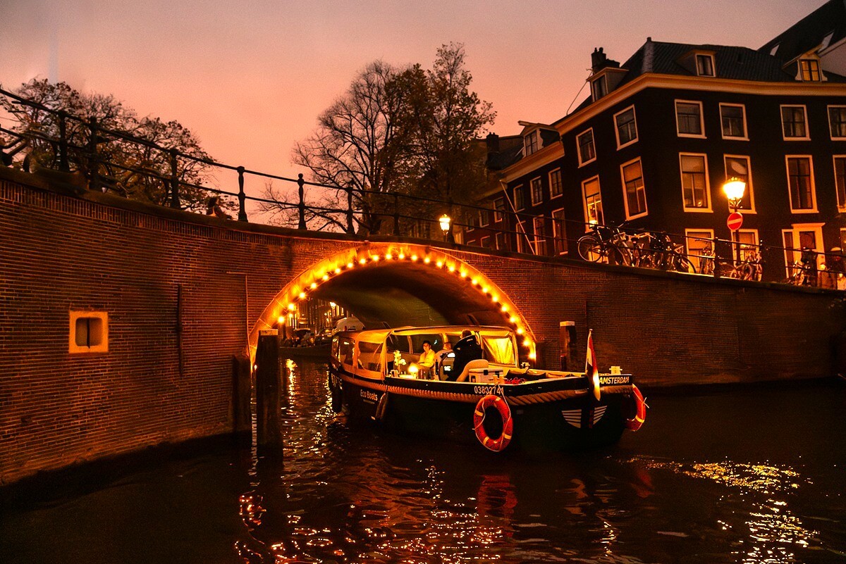 Eco Boats partially covered passing under illuminated bridge in winter