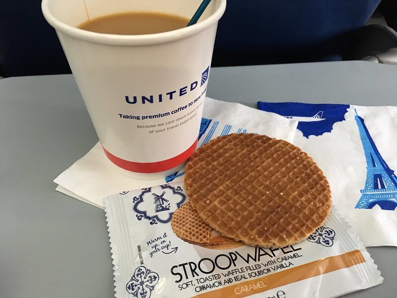 A photo of a stroopwafel and coffee on a United flight